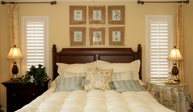Beige bedroom with white plantation shutters covering windows in Clearwater 